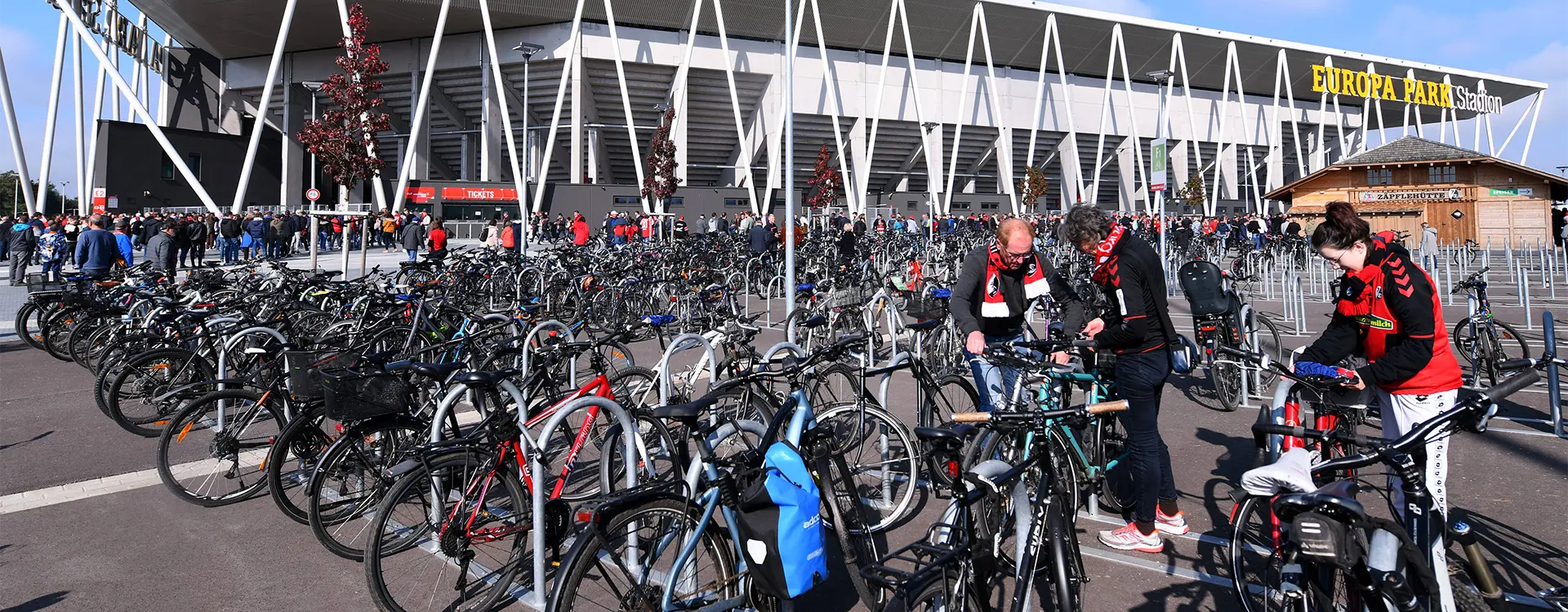 Menschen schließen ihre Fahrräder vor einem Spiel an den Fahrradständern vor dem Stadion ab. (Foto)