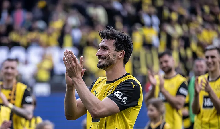 Mats Hummels klatscht in seinem schwarz-gelben Trikot, im Hintergrund sind Teamkollegen und Fans zu sehen. (Foto)