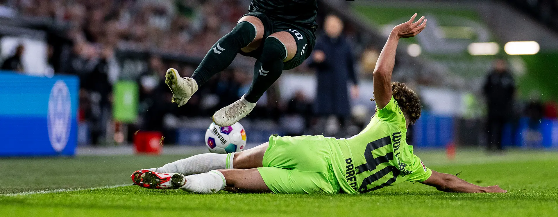 Ein Torwart in einem grünen Trikot, der auf dem Boden rutscht, um einen angreifenden gegnerischen Spieler abzuwehren. (Foto)