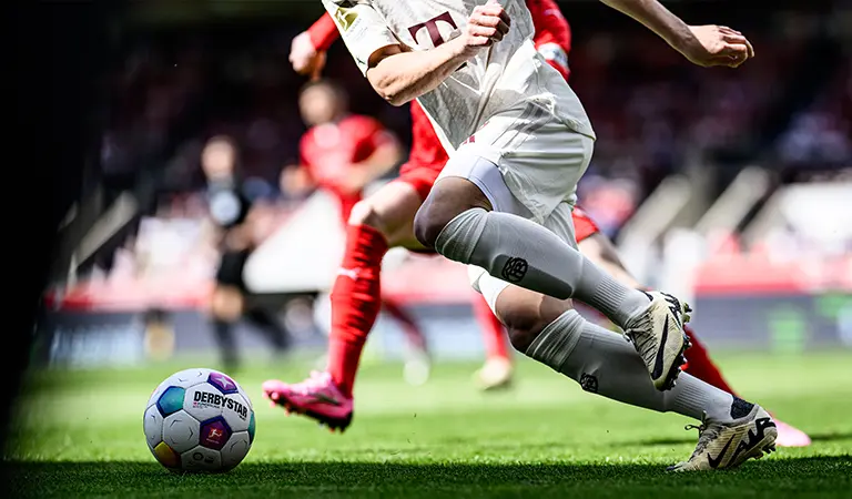 Ein Spieler, der einem Ball hinterherläuft, während die gegnerischen Spieler im Hintergrund hinter ihm herlaufen. (Foto)