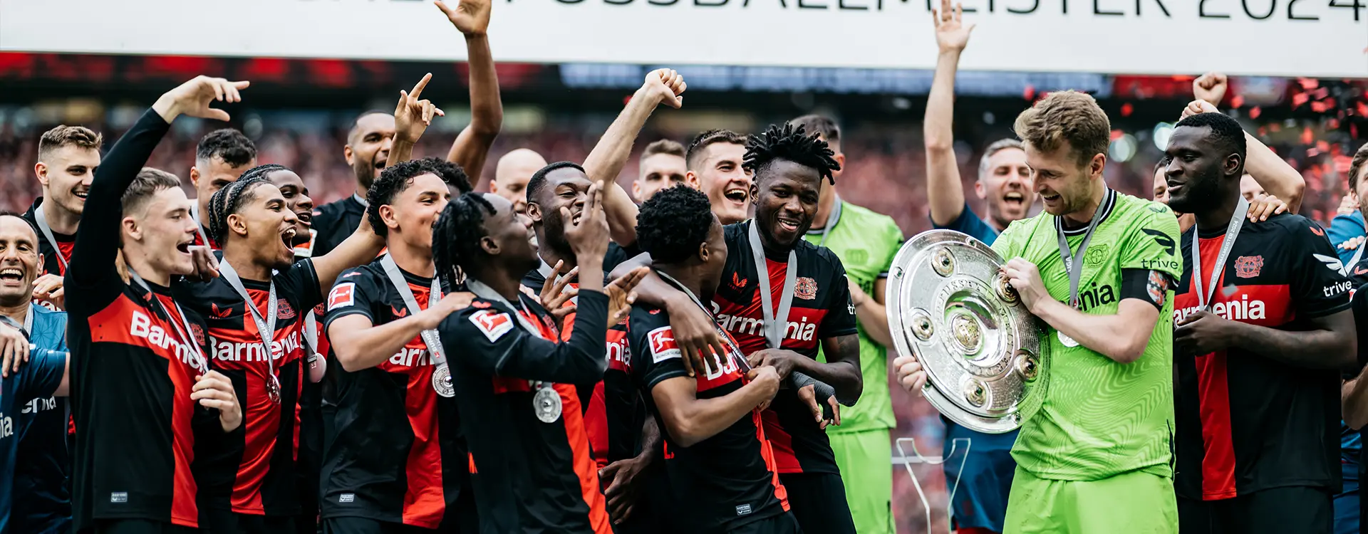 Die Mannschaft des FC Bayern Leverkusen feiert ihren Sieg mit der Meisterschale in ihrer Mitte. (Foto)