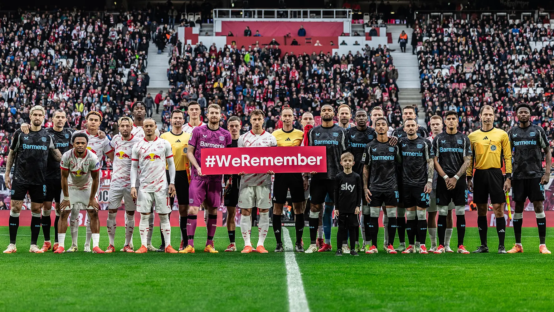 Beide Mannschaften des 19. Spieltags von RB Leipzig und Bayer 04 Leverkusen halten auf dem Spielfeld ein kleines "#WeRemember"-Banner hoch. (Foto)