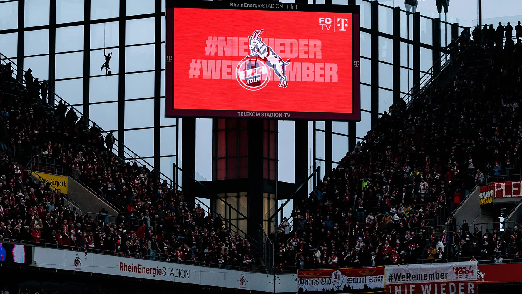 Eine große rote Leinwand mit #NieWieder und #WeRemember mit den Logos der spielenden Mannschaften im Hintergrund. (Foto)