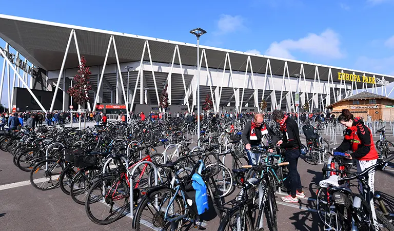 People locking up their bikes on the bike racks in front of the stadium before a game. (Photo)