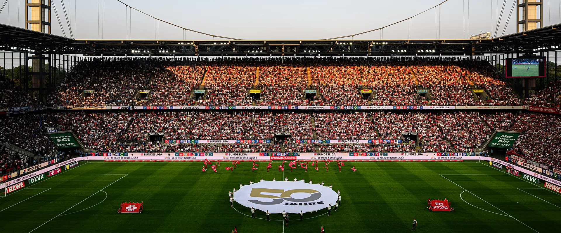 A football field with players in red jerseys on the field, and full stands with spectators. (Photo)