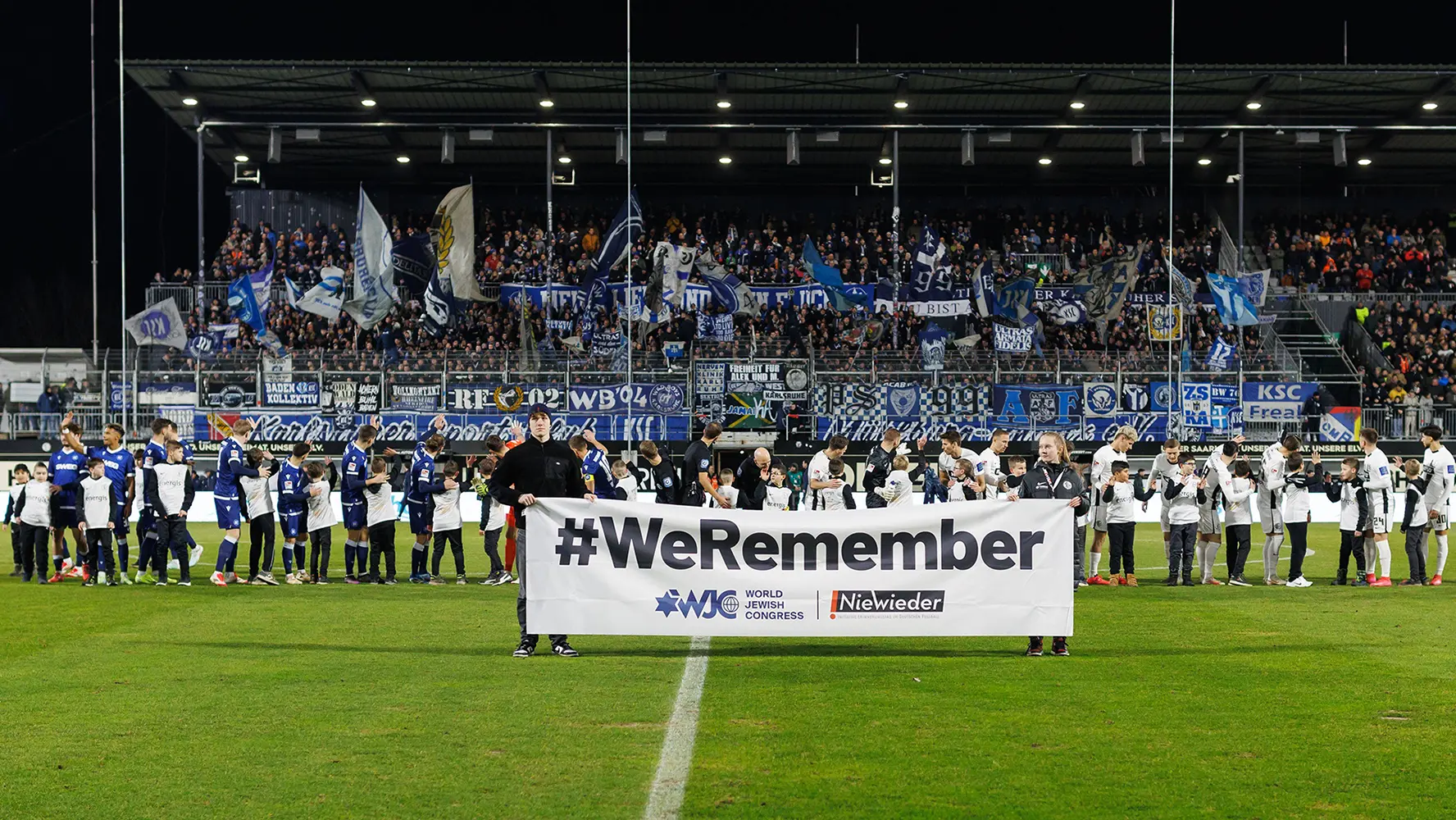 Two teamsters hold up a large banner with "#WeRemember" on the field.&nbsp; (Photo)