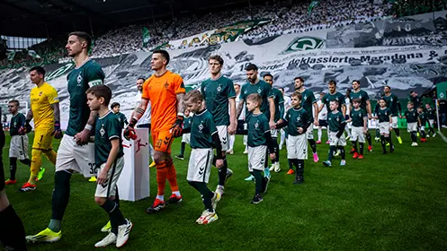 SV Werder Bremen and 1. FC Heidenheim players walking out onto the field, holding hands with junior players in the same jerseys. (Photo)