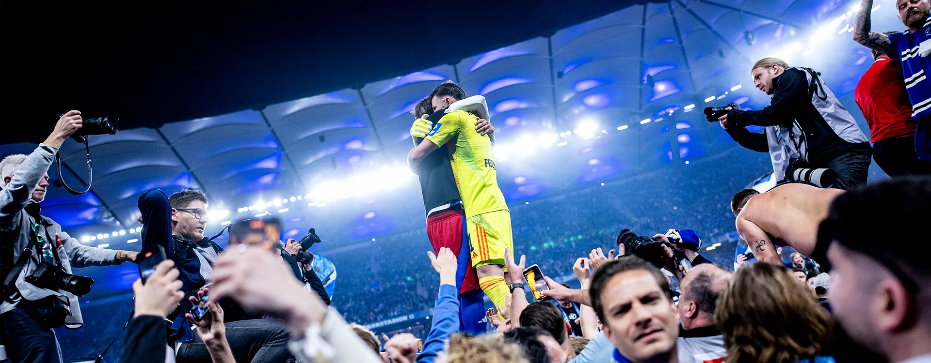Der Torwart des HSV und ein weiterer Spieler umarmen sich nach dem Aufstieg auf dem Platz. (Foto)