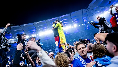 Der Torwart des HSV und ein weiterer Spieler umarmen sich nach dem Aufstieg auf dem Platz. (Foto)