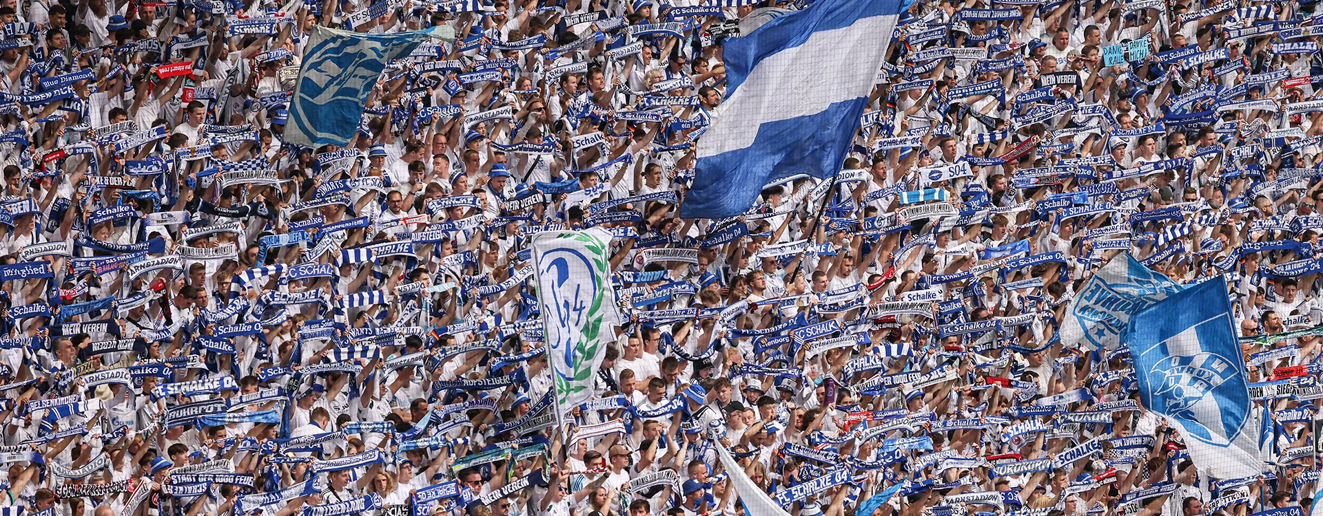 FC Schalke 04 fans holding up their team's flags and scarves in the stands. (Photo)