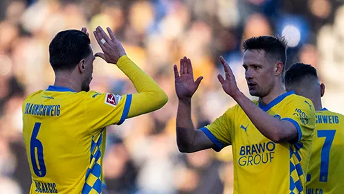 Two players from Eintracht Braunschweig are about to high-five each other. (Photo)